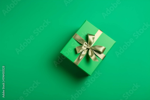 Gift box with satin ribbon and bow on green background. Holiday gift with copy space. Birthday or Christmas present, flat lay, top view. Christmas giftbox concept