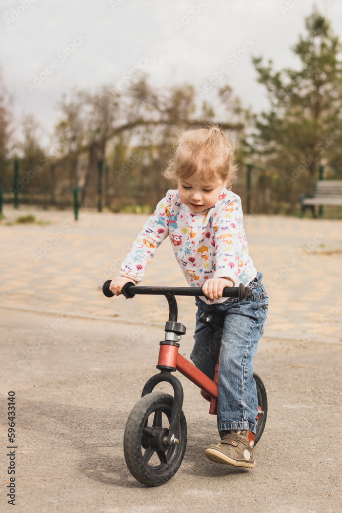cheerful little child girl riding a bike in the city park in sunny day outdoors cheerful little child girl riding a bike in the city park in sunny day outdoors