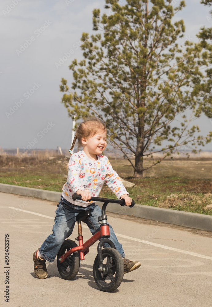 smiling happy little child girl riding a bike in the city park in sunny day outdoors smiling happy little child girl riding a bike in the city park in sunny day outdoors