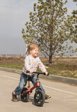 smiling happy little child girl riding a bike in the city park in sunny day outdoors