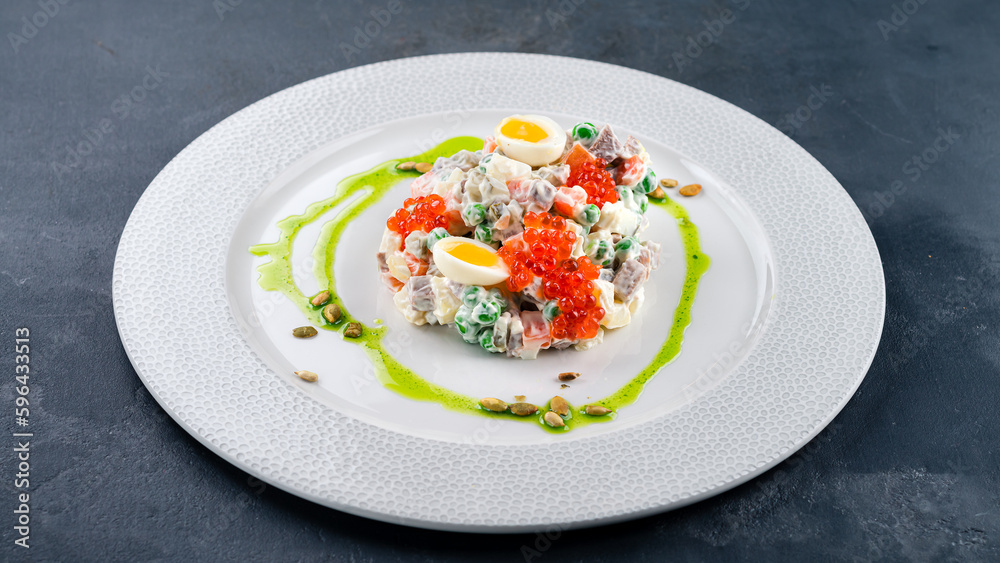 Salad Olivier from boiled potatoes, carrots, green peas, cucumbers, eggs, chicken ham, mayonnaise served with red caviar and quail eggs. Salad Olivier from boiled potatoes, carrots, green peas, cucumbers, eggs, chicken ham, mayonnaise served with red caviar and quail eggs.