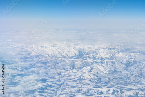 Aerial view of the Siberian hills and mountains covered with snow in the tundra. Siberia  Far East of Russia. Snow-covered tundra in the Arctic.