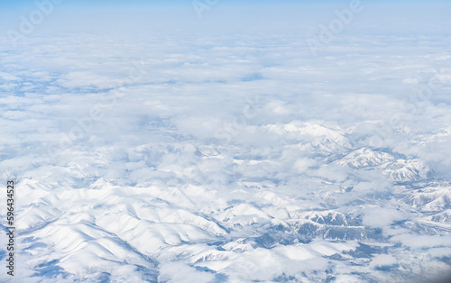 Aerial view of the Siberian hills and mountains covered with snow in the tundra. Siberia, Far East of Russia. Snow-covered tundra in the Arctic. © Tishina