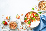 Yogurt with granola, nuts and strawberries on white. Healthy snack or breakfast, fruit salad. Top view with copy space.