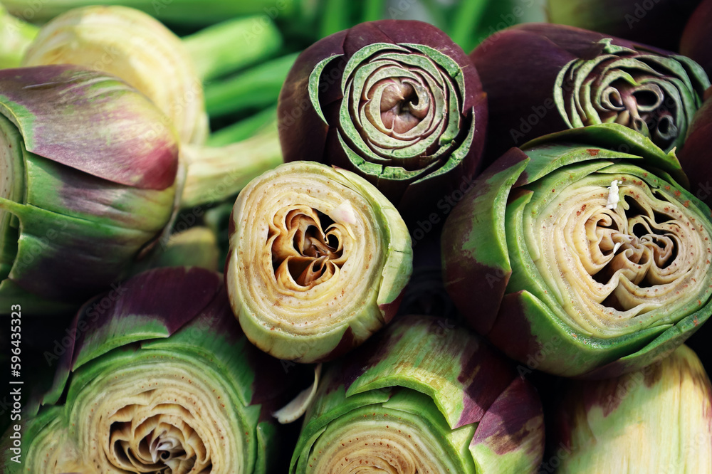 Fototapeta premium Close up of organic peeled artichokes in a box at outdoor farmers market. Cynara cardunculus var. Scolymus. Vegan food and healthy nutrition concept. Artichoke heart for sale in the street of Italy.