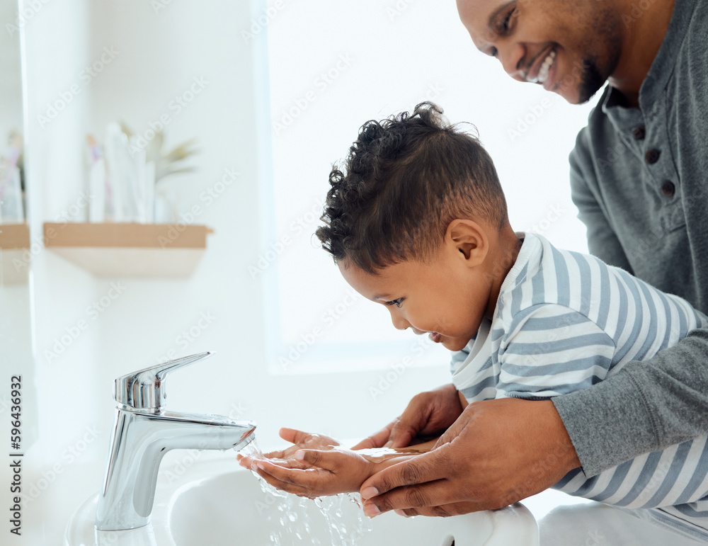 Wash them thoroughly. Shot of an adorable little boy washing his hands with the help of his father at home. Wash them thoroughly. Shot of an adorable little boy washing his hands with the help of his father at home.