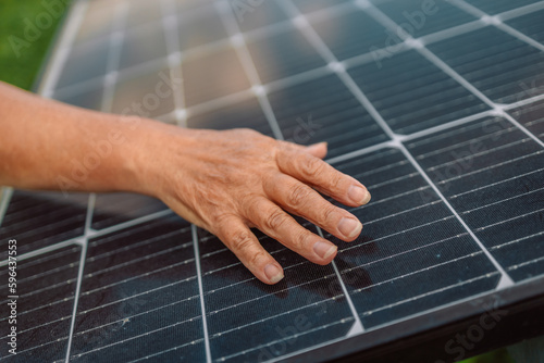Close up of an young engineer hand is checking an operation of sun and cleanliness of photovoltaic solar panels.