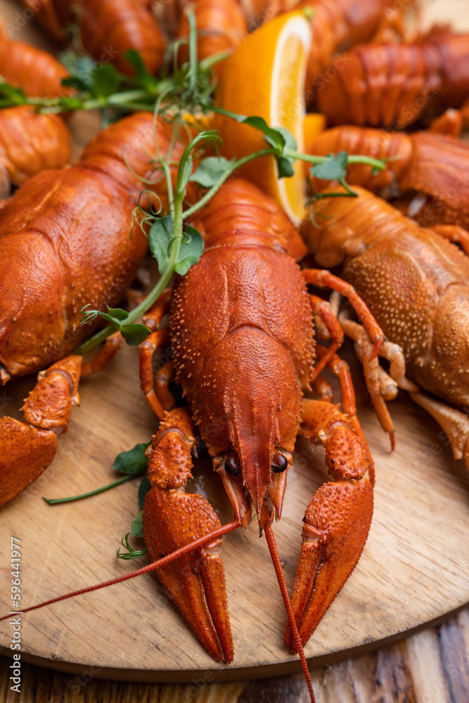 Boiled crayfish with lemon, dill and herbs on a wooden cutting board on blue wooden background. Crayfish dish Boiled crayfish with lemon, dill and herbs on a wooden cutting board on blue wooden background. Crayfish dish