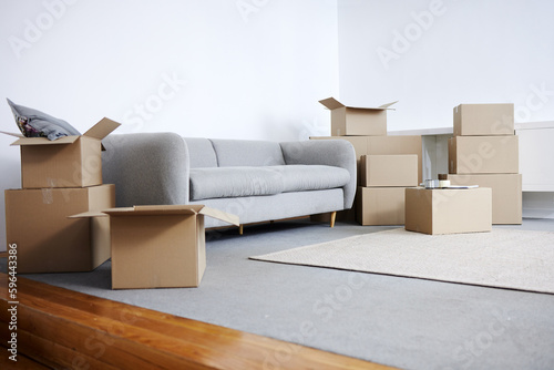 Time to unpack. Shot of cardboard boxes and a sofa in an empty living room during the day. © Azeemud/peopleimages.com