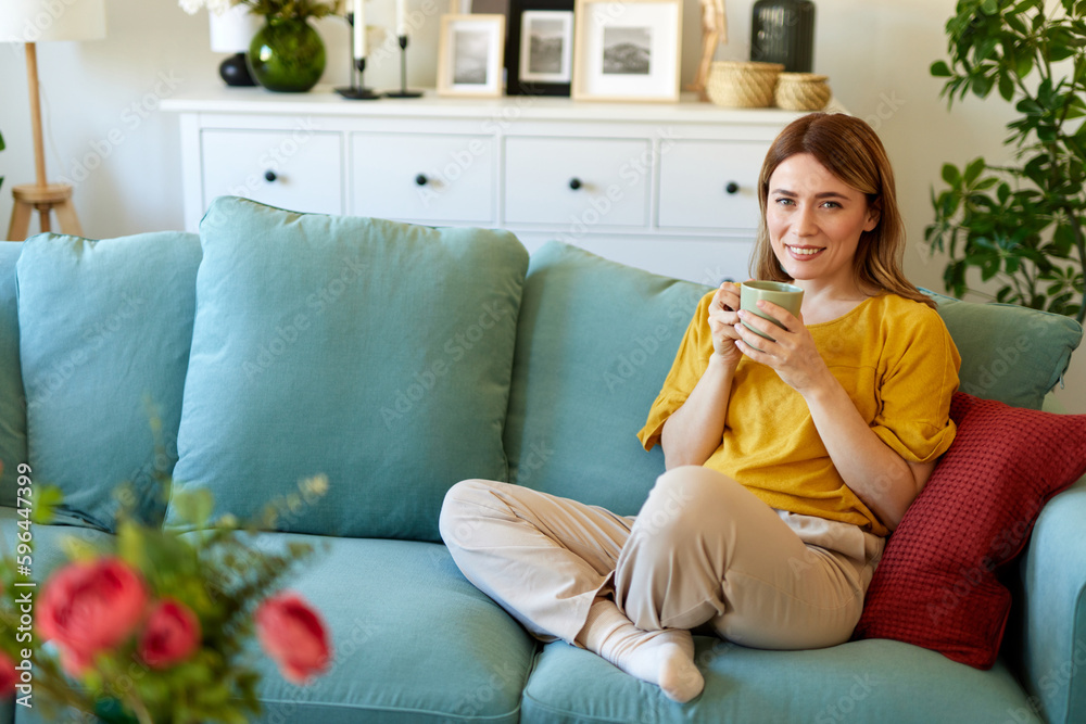 Obraz premium An attractive young woman relaxing at home drinking coffee