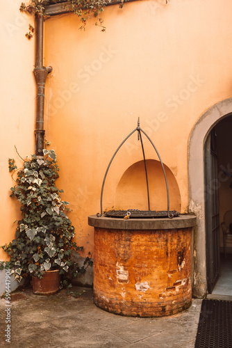 An old well near the orange wall of a house on an old street in Italy. High quality photo © Shi 