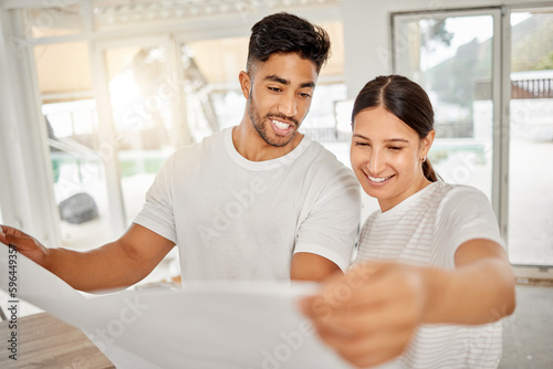 This is going to look so good. Shot of a young couple standing together and looking at building plans for their home.
