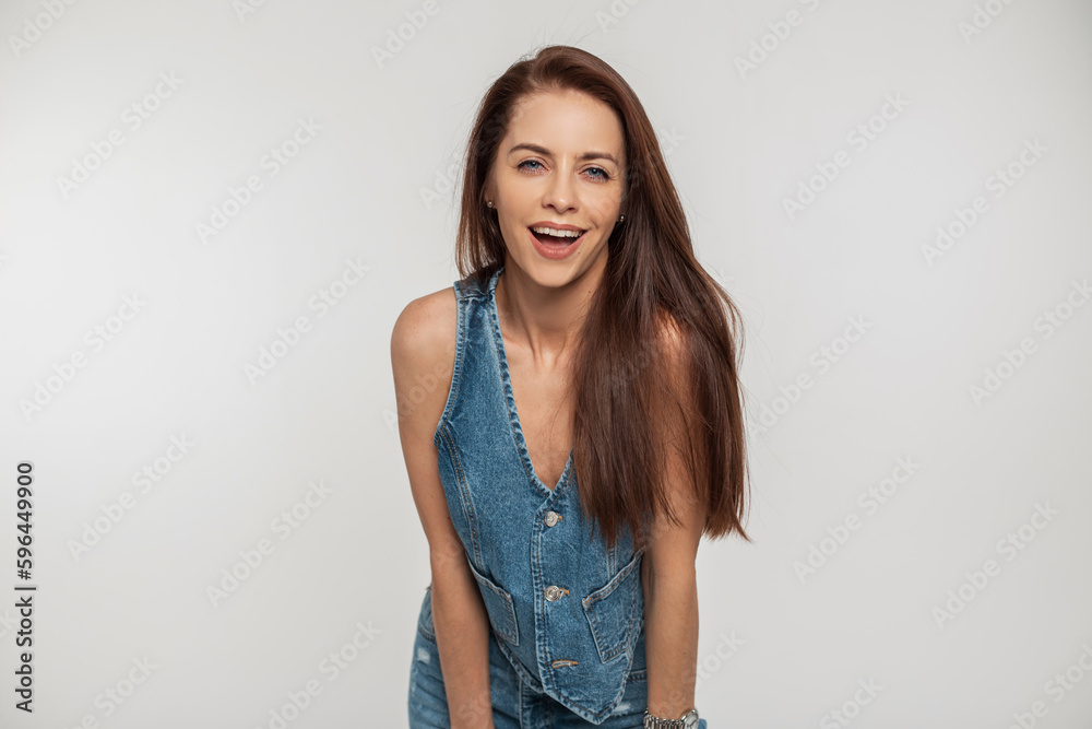 Cheerful beautiful young woman with positive emotions in fashion retro denim clothes with a denim jacket and jeans on a white background Cheerful beautiful young woman with positive emotions in fashion retro denim clothes with a denim jacket and jeans on a white background