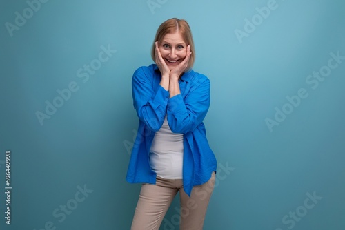funny pretty blond mature woman in on blue background with copyspace