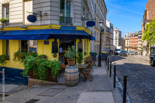 Cozy street with tables of cafe in quarter Montmartre in Paris, France. Architecture and landmark of Paris. Cozy Paris cityscape.