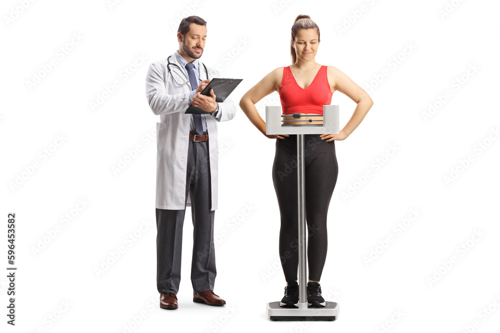 Young woman in sportswear weighing on a medical scale and male doctor writing a document