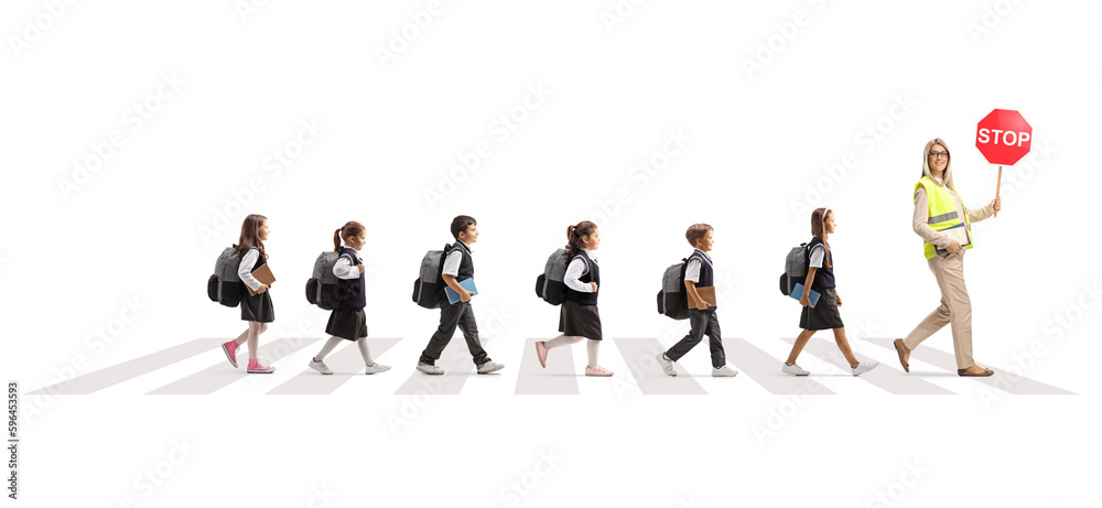 Full length profile shot of a teacher with stop sign and schoolchildren crossing road at a pedestrian crossing Full length profile shot of a teacher with stop sign and schoolchildren crossing road at a pedestrian crossing