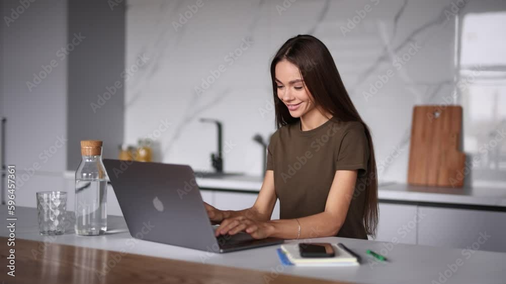 Young woman working on laptop in the kitchen Young woman working on laptop in the kitchen