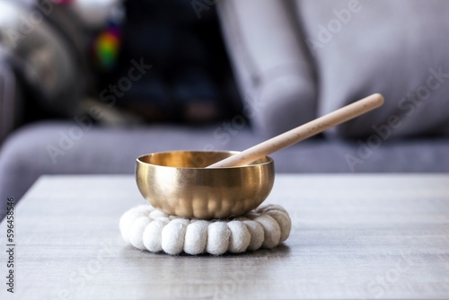 A portrait of a tibetan singing bowl, also called a himalayan bowl, with a mallet standing in it to make a relaxing sound. The object is used for relaxation, meditation and therapy to relieve stress.
