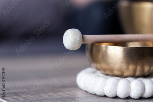 A close portrait of a tibetan singing bowl or himalayan bowl, with a mallet lying on top of it to make a relaxing sound. The object is used for meditation, relaxation and therapy to relieve stress.