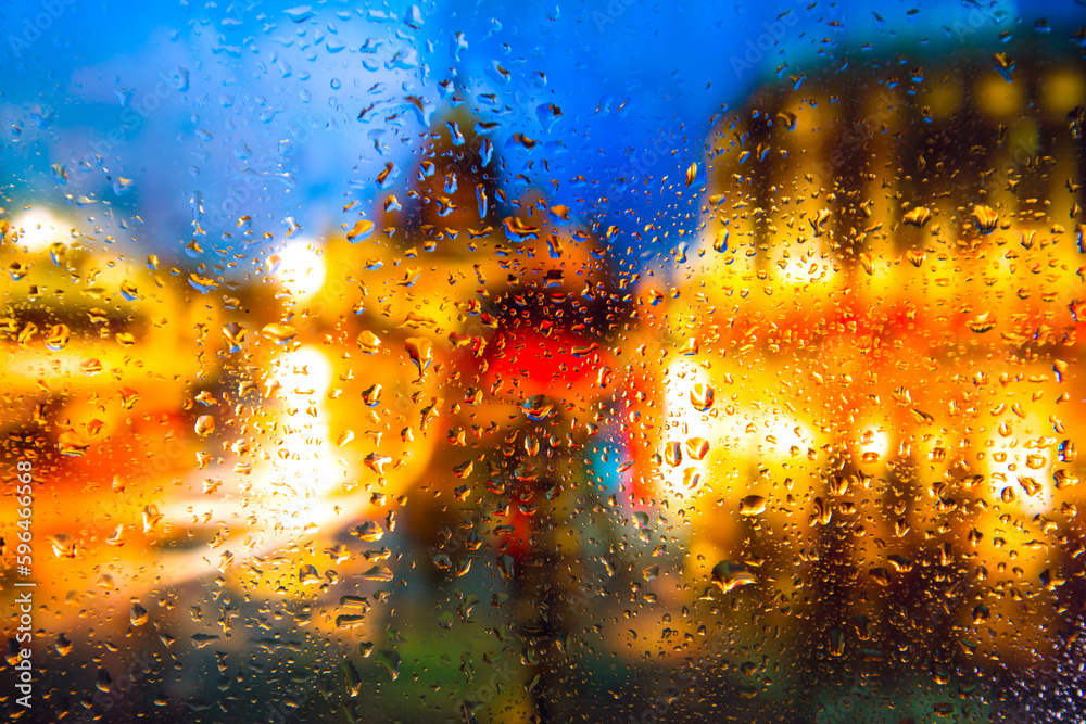 City view through a window on a rainy night,Rain drops on window with road light bokeh, City life in night in rainy season abstract background. Focus on drops on glass	