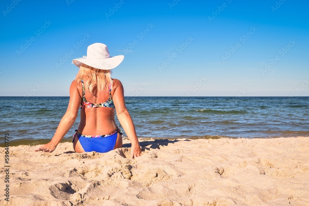 Beautiful holiday sunny concept with a woman by the sea. Blond-haired girl on the beach in Jastarnia, Poland.