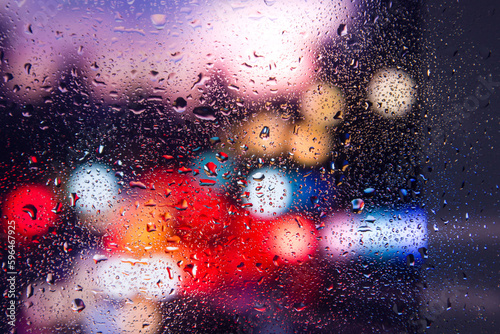 City view through a window on a rainy night Rain drops on window with road light bokeh  City life in night in rainy season abstract background. Focus on drops on glass 