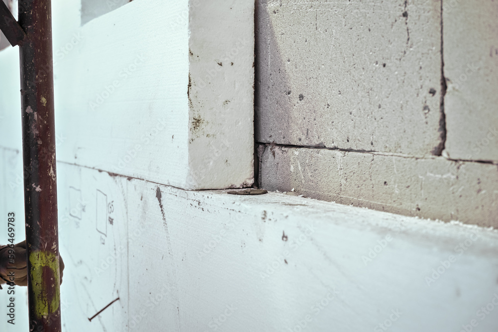 White polystyrene foam board blocks for heat insulation on bare concrete wall at construction site, closeup detail White polystyrene foam board blocks for heat insulation on bare concrete wall at construction site, closeup detail