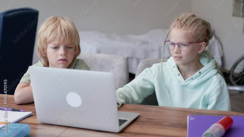 Online school class, siblings pupils boy and girl learning together remotely online at home, looking to laptop, speaking with teacher or tutor using internet Online school class, siblings pupils boy and girl learning together remotely online at home, looking to laptop, speaking with teacher or tutor using internet