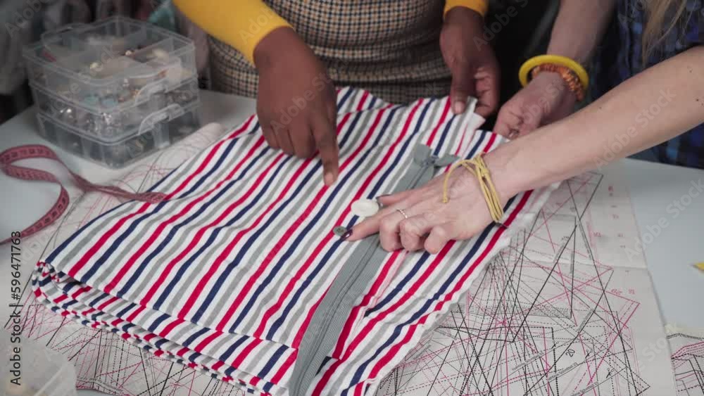 A clothing designer and assistants match a button to a striped fabric. A clothing designer and assistants match a button to a striped fabric.