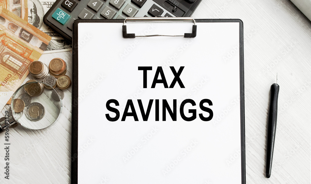 Notepad with an inscription TAX SAVINGS. Conceptual image, business accessories, calculator isolated on the desktop. Finance or business concept. Notepad with an inscription TAX SAVINGS. Conceptual image, business accessories, calculator isolated on the desktop. Finance or business concept.
