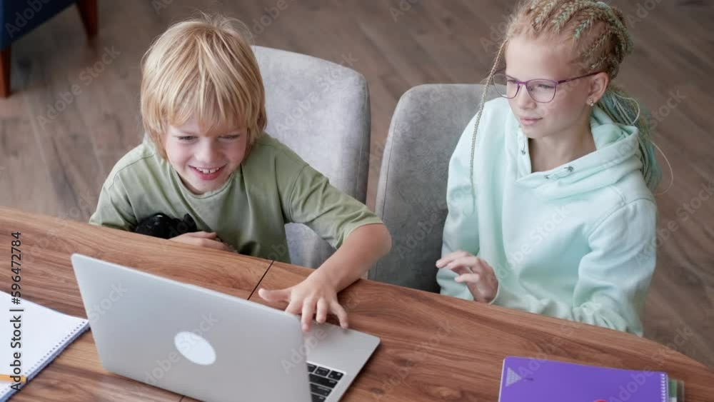 Online school class, siblings pupils boy and girl learning together remotely online at home, looking to laptop, speaking with teacher or tutor using internet Online school class, siblings pupils boy and girl learning together remotely online at home, looking to laptop, speaking with teacher or tutor using internet