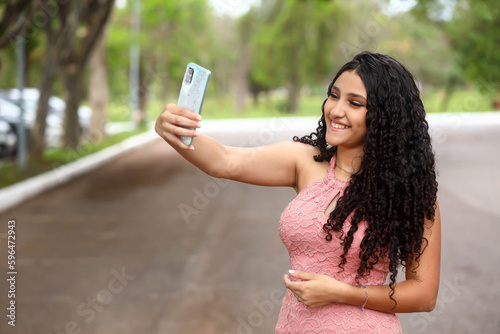 girl taking selfie by cell phone, latina, happy, smartphone, front-facing camera, social media, Instagram photo