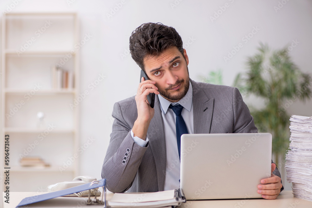 Young male employee and too much work in the office Young male employee and too much work in the office