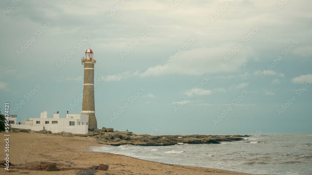 portrait of san ignacio lighthouse, uruguay a cloudy afternoon in front of the rough sea with waves
