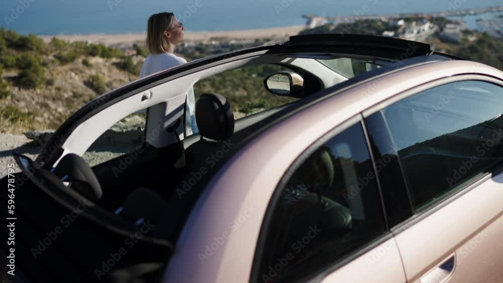 Caucasian female arrived at beautiful place and gets out of convertible car to admire sea view during travel. Eco vehicle and care for the environment. Young woman parked auto while enjoying tourism Caucasian female arrived at beautiful place and gets out of convertible car to admire sea view during travel. Eco vehicle and care for the environment. Young woman parked auto while enjoying tourism