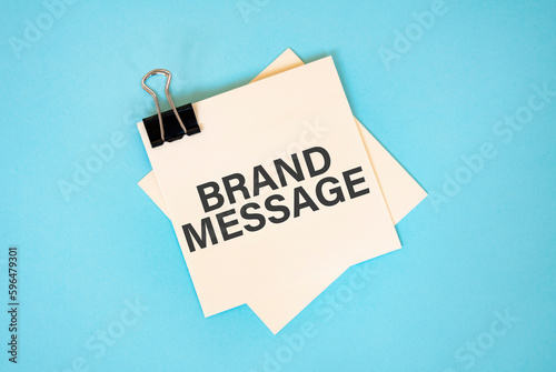 Text BRAND MESSAGE on sticky notes with copy space and paper clip isolated on red background.Finance and economics concept.