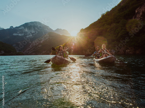 A group of friends enjoying fun and kayaking exploring the calm river, surrounding forest and large natural river canyons during an idyllic sunset. © .shock