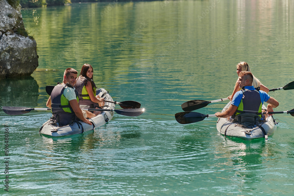 A group of friends enjoying having fun and kayaking while exploring the calm river, surrounding forest and large natural river canyons A group of friends enjoying having fun and kayaking while exploring the calm river, surrounding forest and large natural river canyons