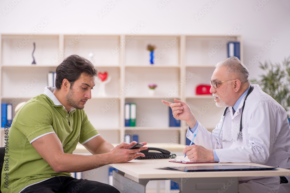 Fototapeta premium Young male patient visiting old male doctor
