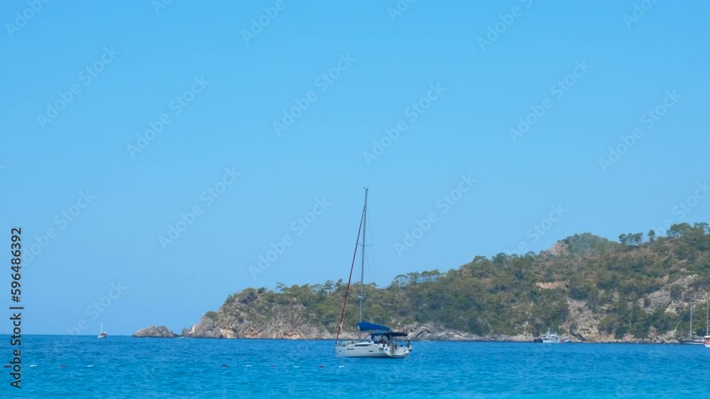 Luxury yacht against tropical coastline. A view of sunny tropical hills with moored yacht with no sails in the day light. Luxury yacht against tropical coastline. A view of sunny tropical hills with moored yacht with no sails in the day light.