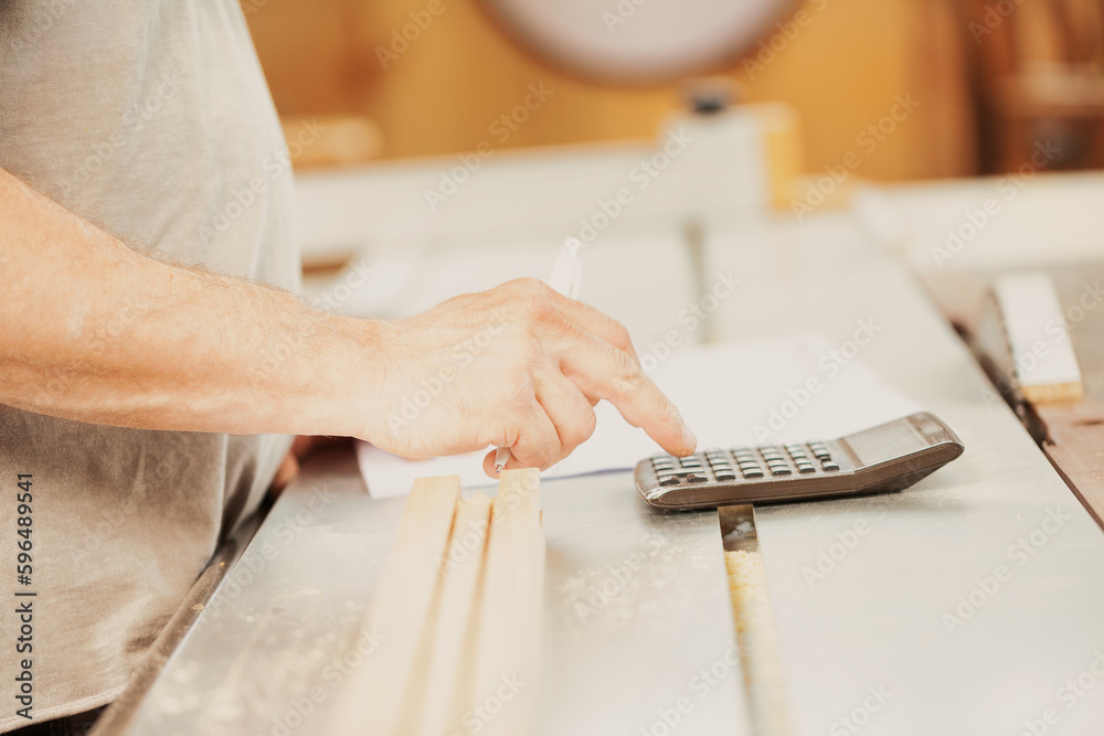 Hand of a worker about to touch the keys of the calculator.