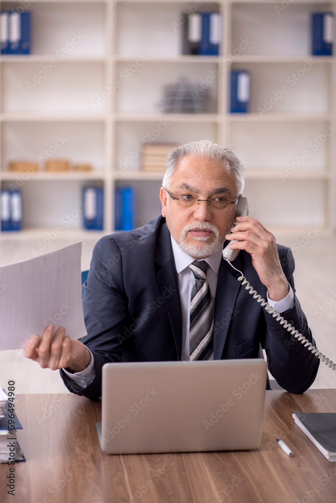 Old male employee working in the office