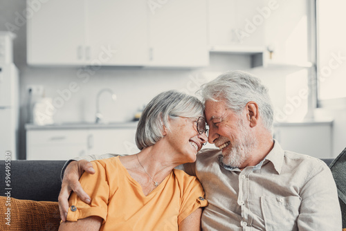 Happy laughing older married couple talking, laughing, standing in home interior together, hugging with love, enjoying close relationships, trust, support, care, feeling joy, tenderness.