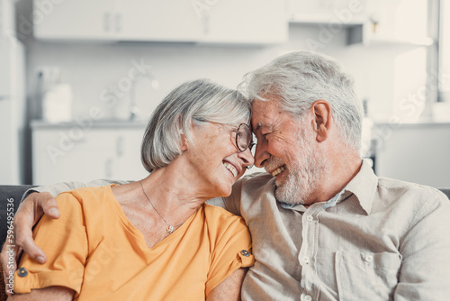 Happy laughing older married couple talking, laughing, standing in home interior together, hugging with love, enjoying close relationships, trust, support, care, feeling joy, tenderness.