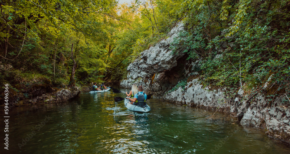 A group of friends enjoying having fun and kayaking while exploring the calm river, surrounding forest and large natural river canyons A group of friends enjoying having fun and kayaking while exploring the calm river, surrounding forest and large natural river canyons
