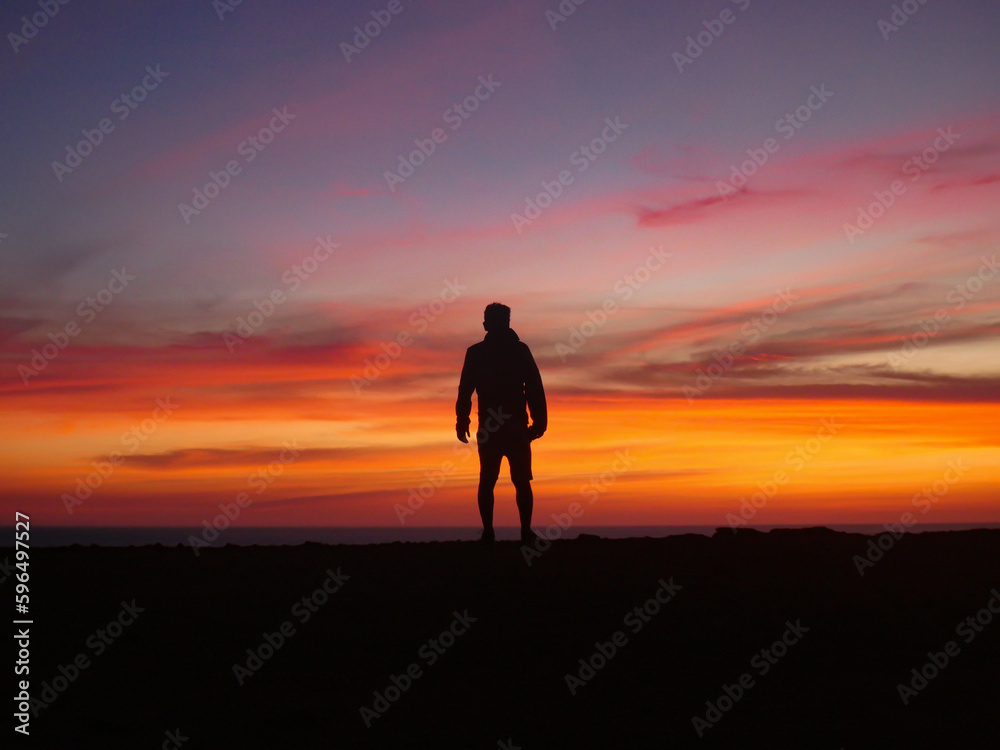 Contemplative View with Middle-Aged Man Silhouette on Cliff Edge and Sunset Sky