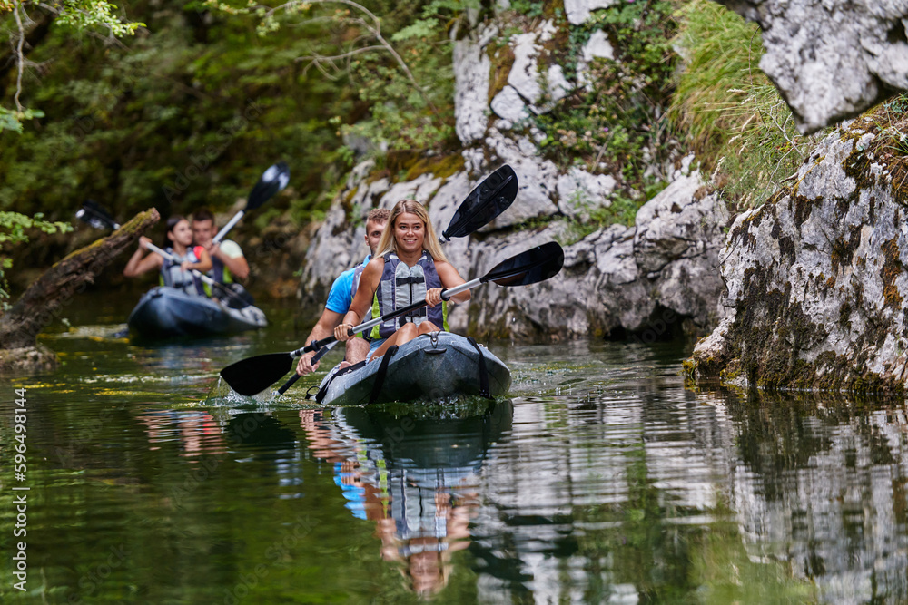A group of friends enjoying having fun and kayaking while exploring the calm river, surrounding forest and large natural river canyons A group of friends enjoying having fun and kayaking while exploring the calm river, surrounding forest and large natural river canyons