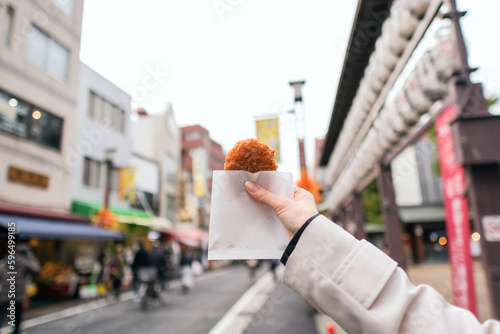 ショッピングストリートでコロッケを食べ歩きする女性の手元のアップ