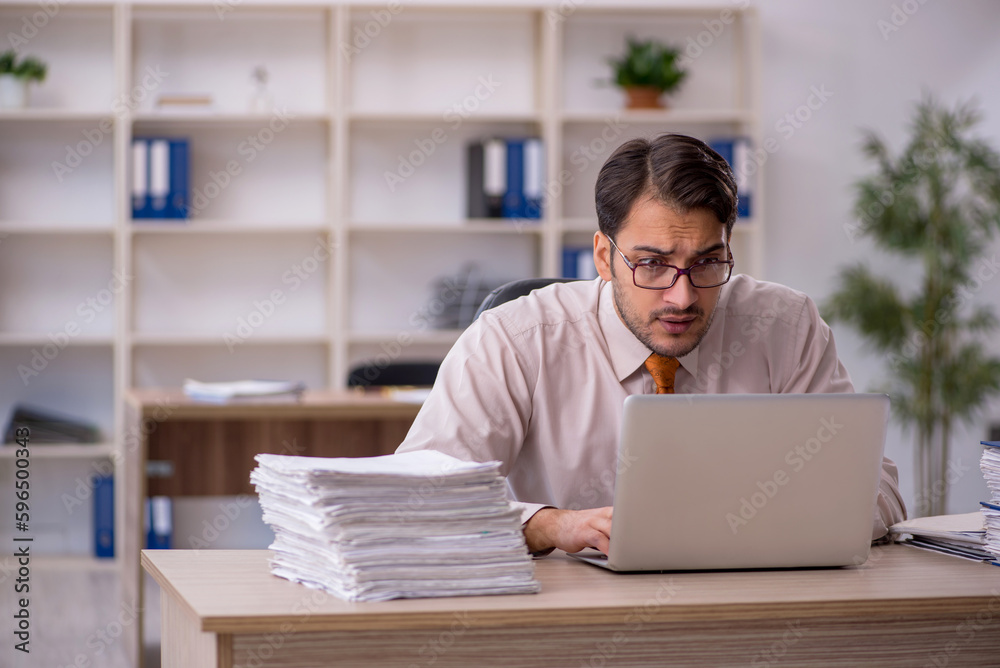 Young male employee and too much work in the office Young male employee and too much work in the office